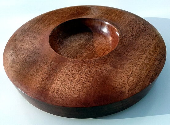 Hands applying oil finish to a wooden bowl