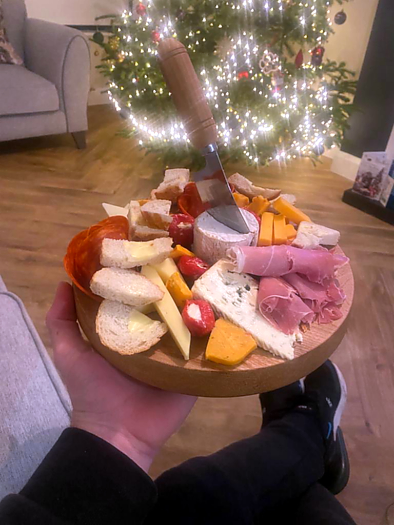 Live-edge wooden cheese board with cheeses arranged on top