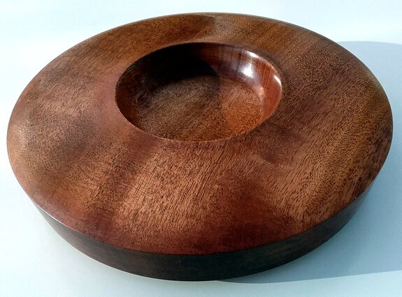 Hands applying oil finish to a wooden bowl